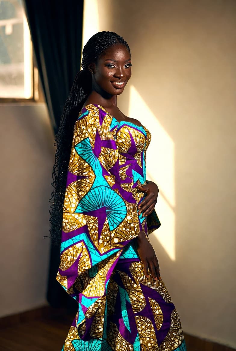 The designer's craftsmanship: a client in a sunlit hand-tailored Ankara wrap